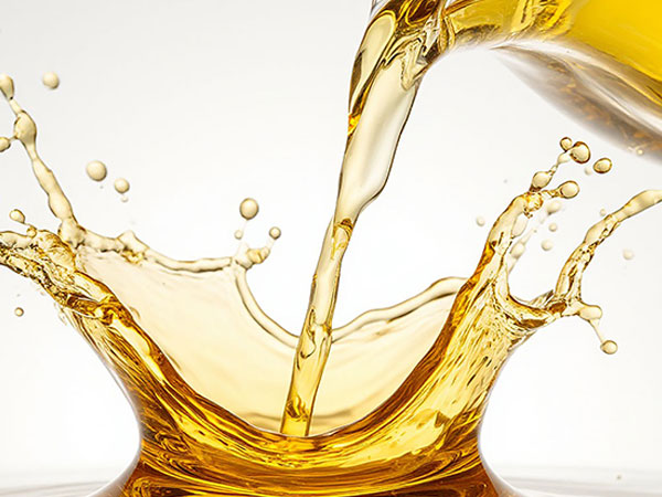 Golden oil is captured as it splashes energetically onto a smooth surface