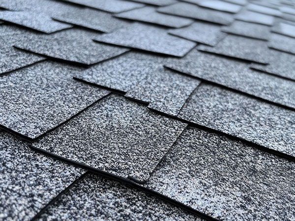 Close-up view of gray asphalt roof shingles in overlapping pattern